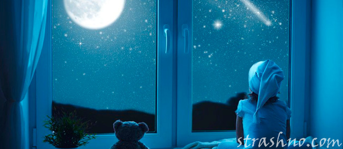 ребенок смотрит в окно на ночное небо