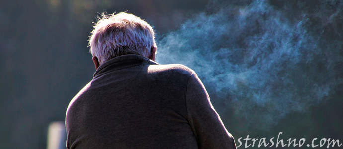 мужчина курит у окна